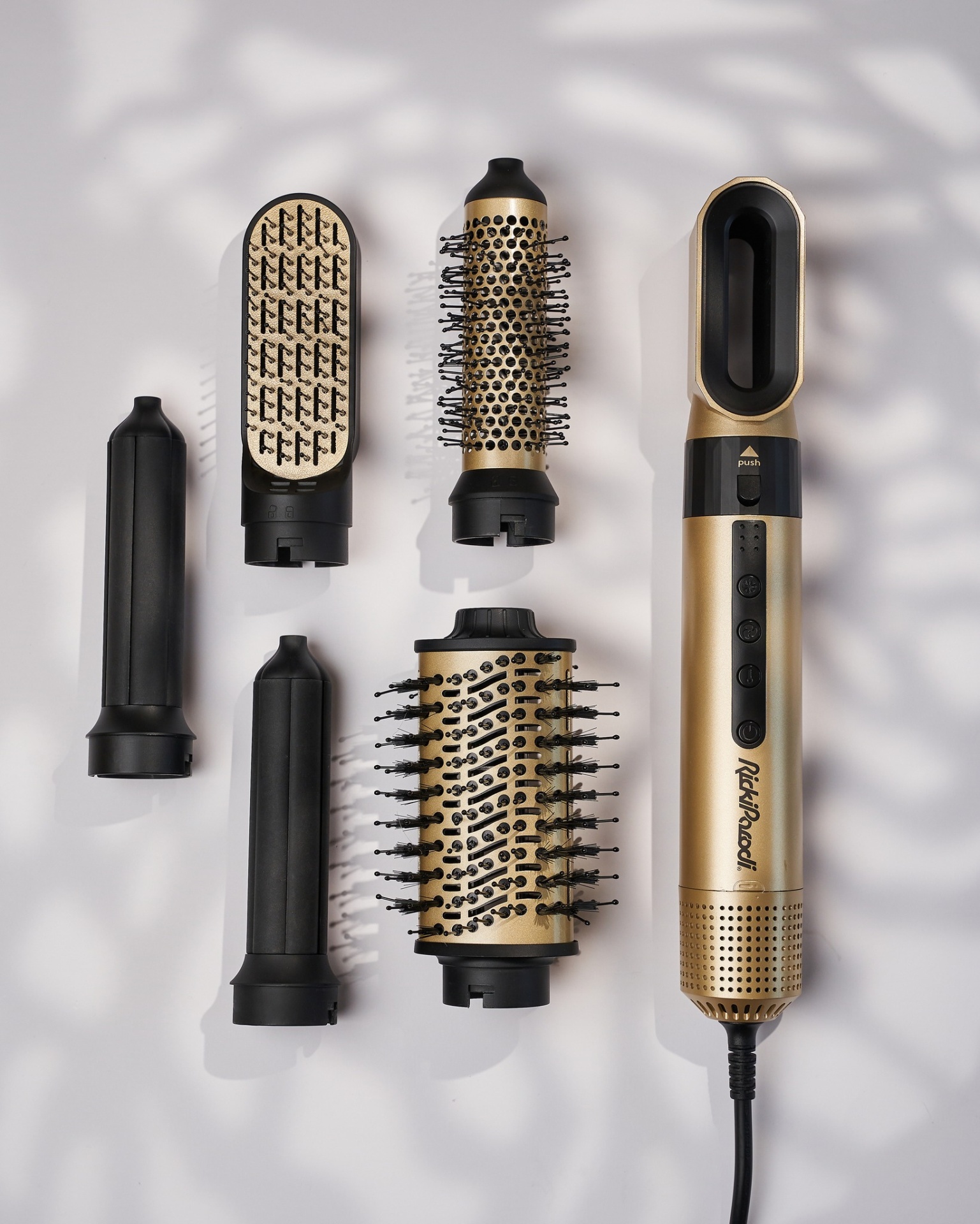 Modelador de cabelo dourado e preto com vários acessórios sobre fundo branco