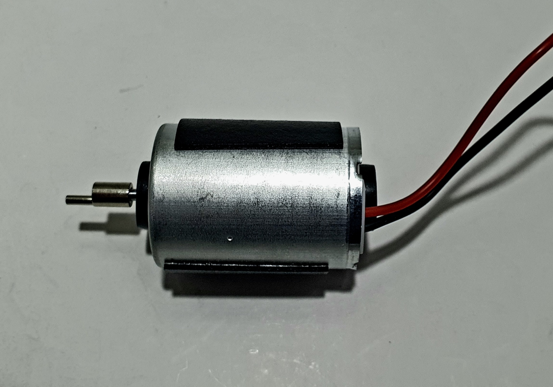 Motor elétrico cilíndrico metálico com fio vermelho e preto