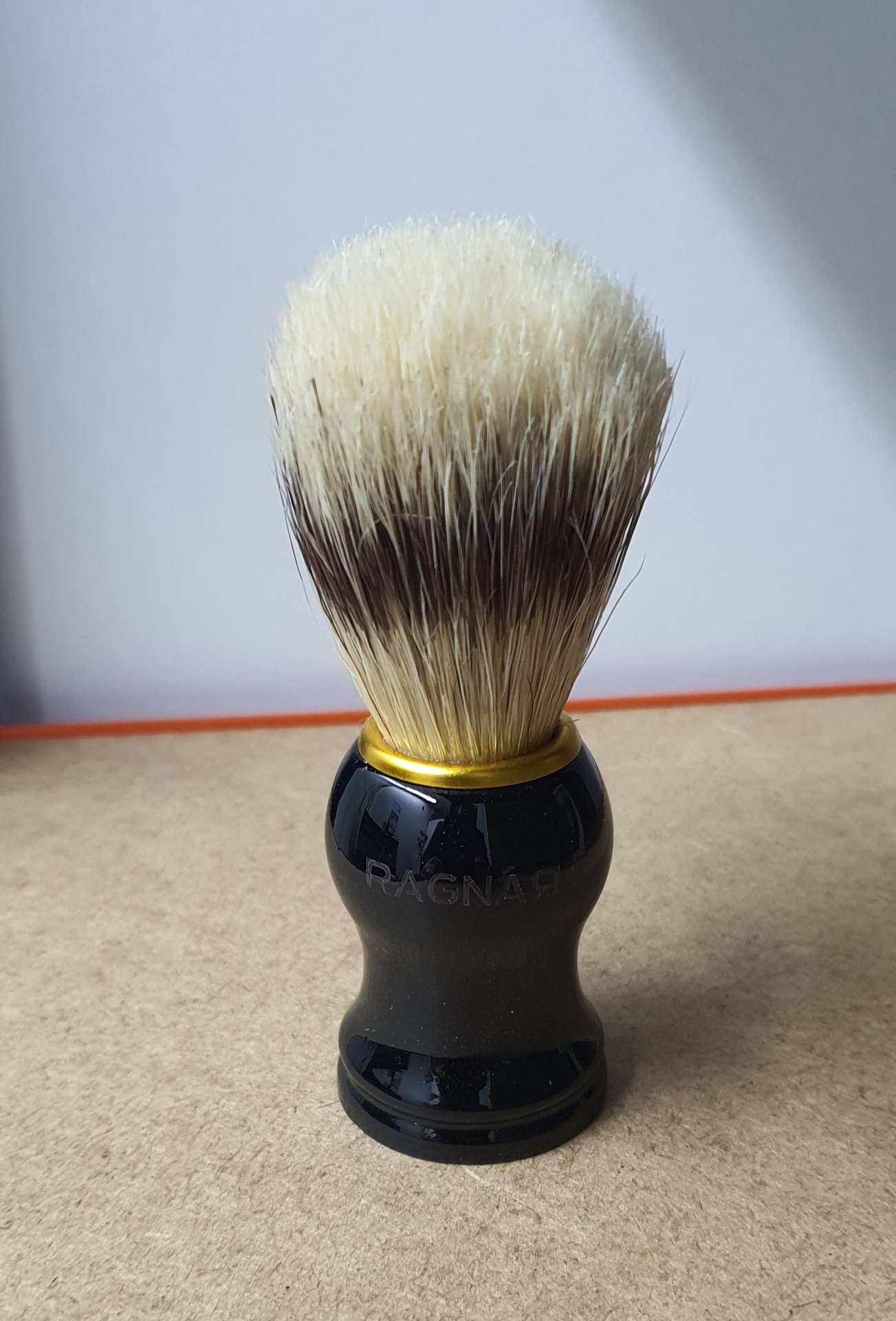 Pincel de barbear com cerdas claras e escuras e cabo preto brilhante