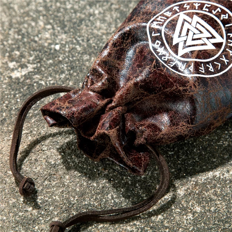 Bolsa de cordão de couro castanho com símbolo branco sobre superfície de pedra