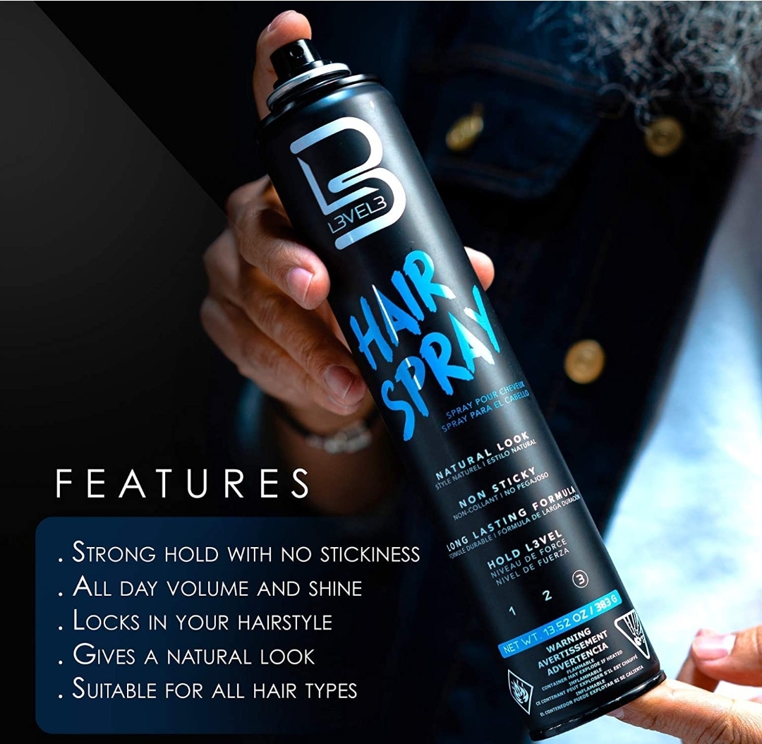 Frasco preto de spray de cabelo LEVEL 3 com texto azul e branco, segurado por uma mão, fundo desfocado