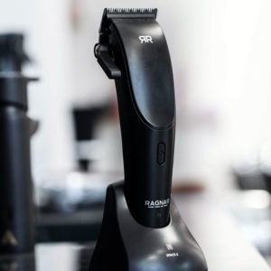 Máquina de cortar cabelo preta com lâmina metálica e suporte de carregamento preto