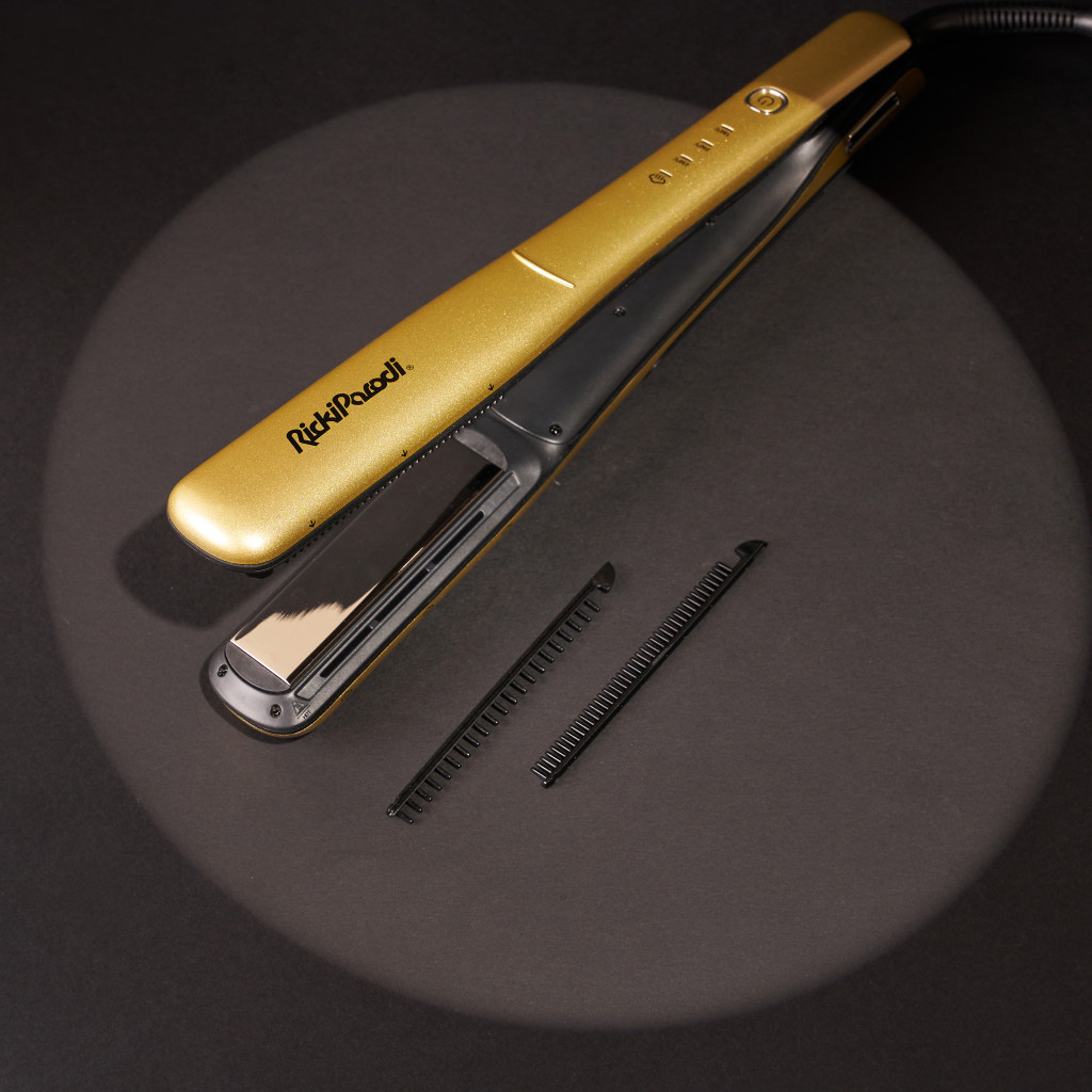 Prancha de alisar cabelo dourada e preta com peças de plástico ao lado