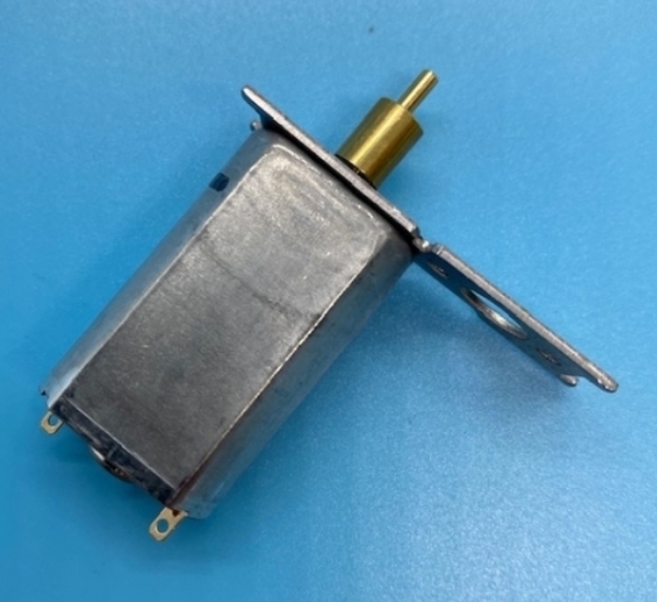 Motor elétrico pequeno metálico com eixo dourado e base metálica sobre superfície azul