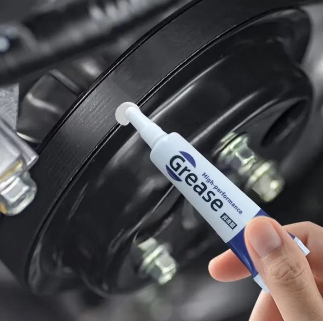 Tubo de graxa de alta performance próximo a peça metálica preta com parafusos