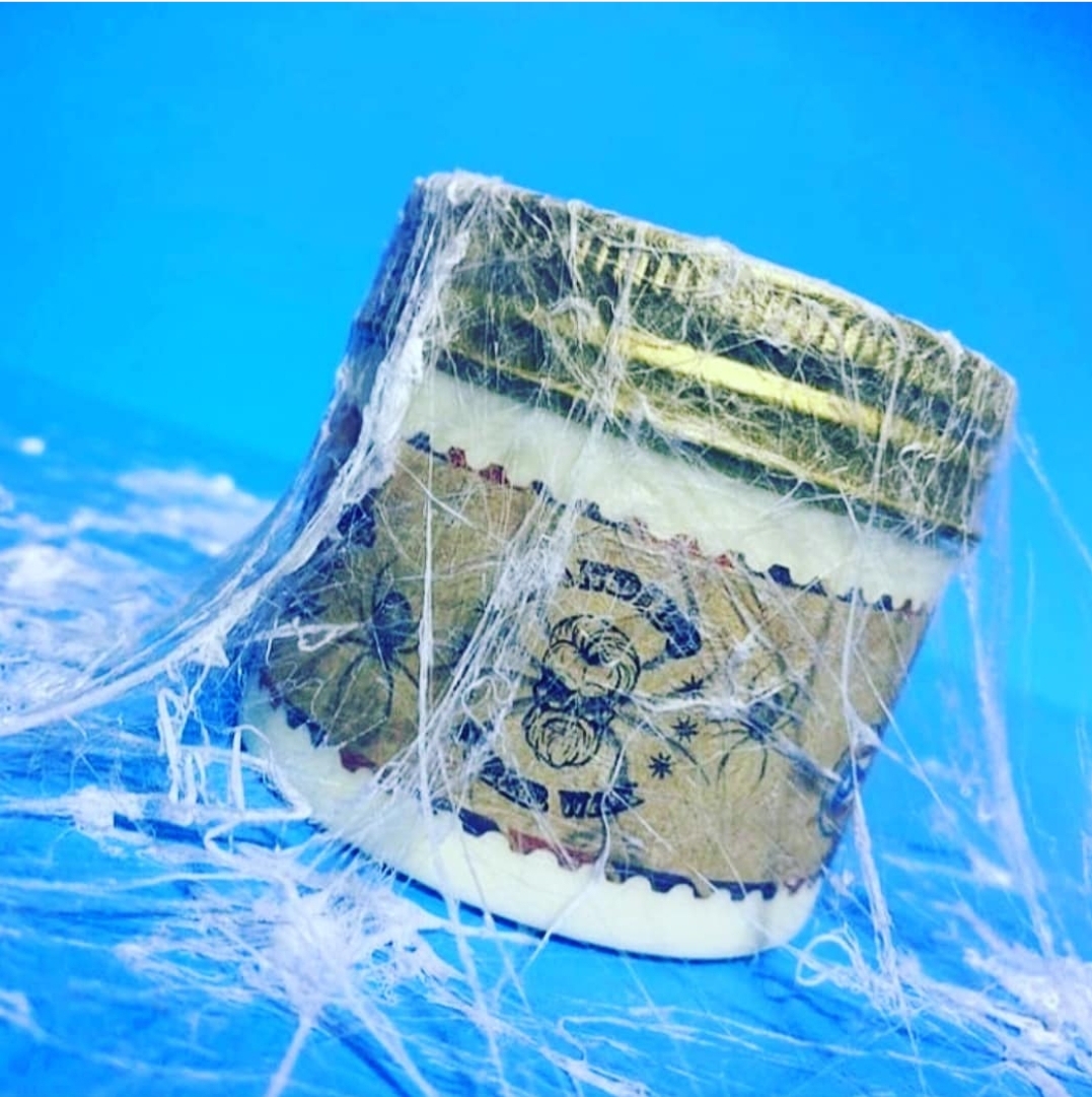 pote de vidro com tampa dourada envolto em teias de aranha