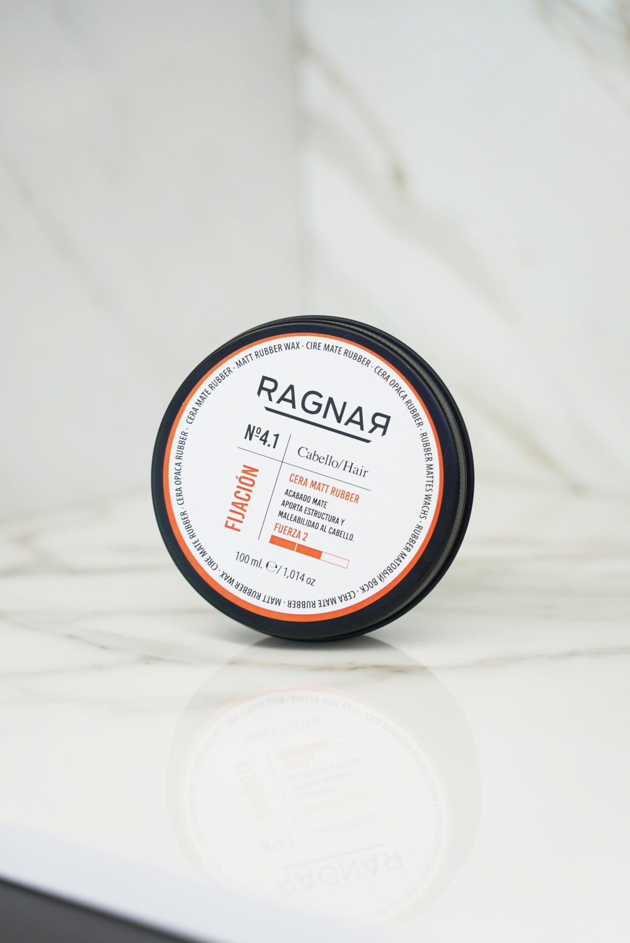 Cera para cabelo RAGNAЯ com tampa preta sobre mármore branco