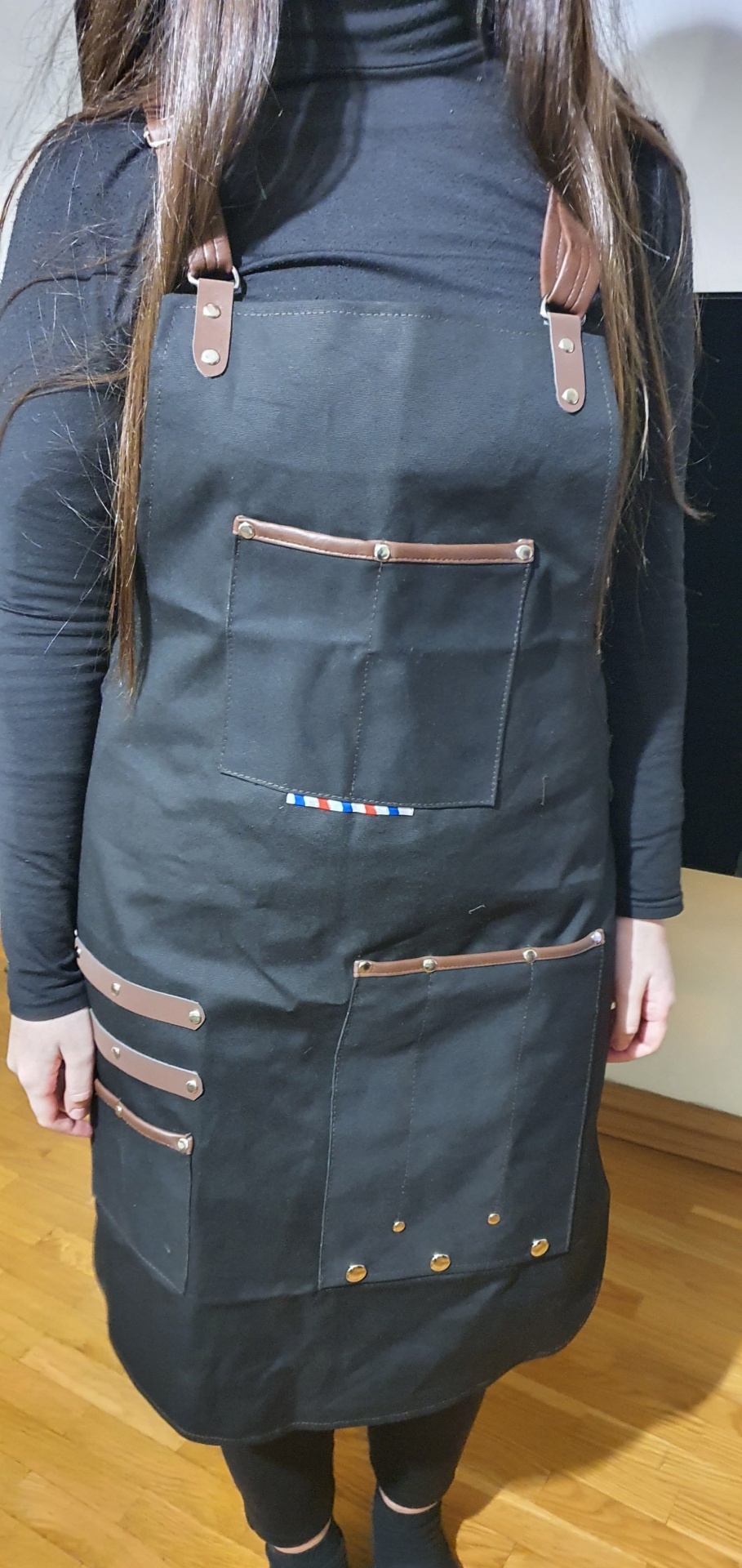 Avental preto com alças e detalhes de couro castanho e bolsos frontais