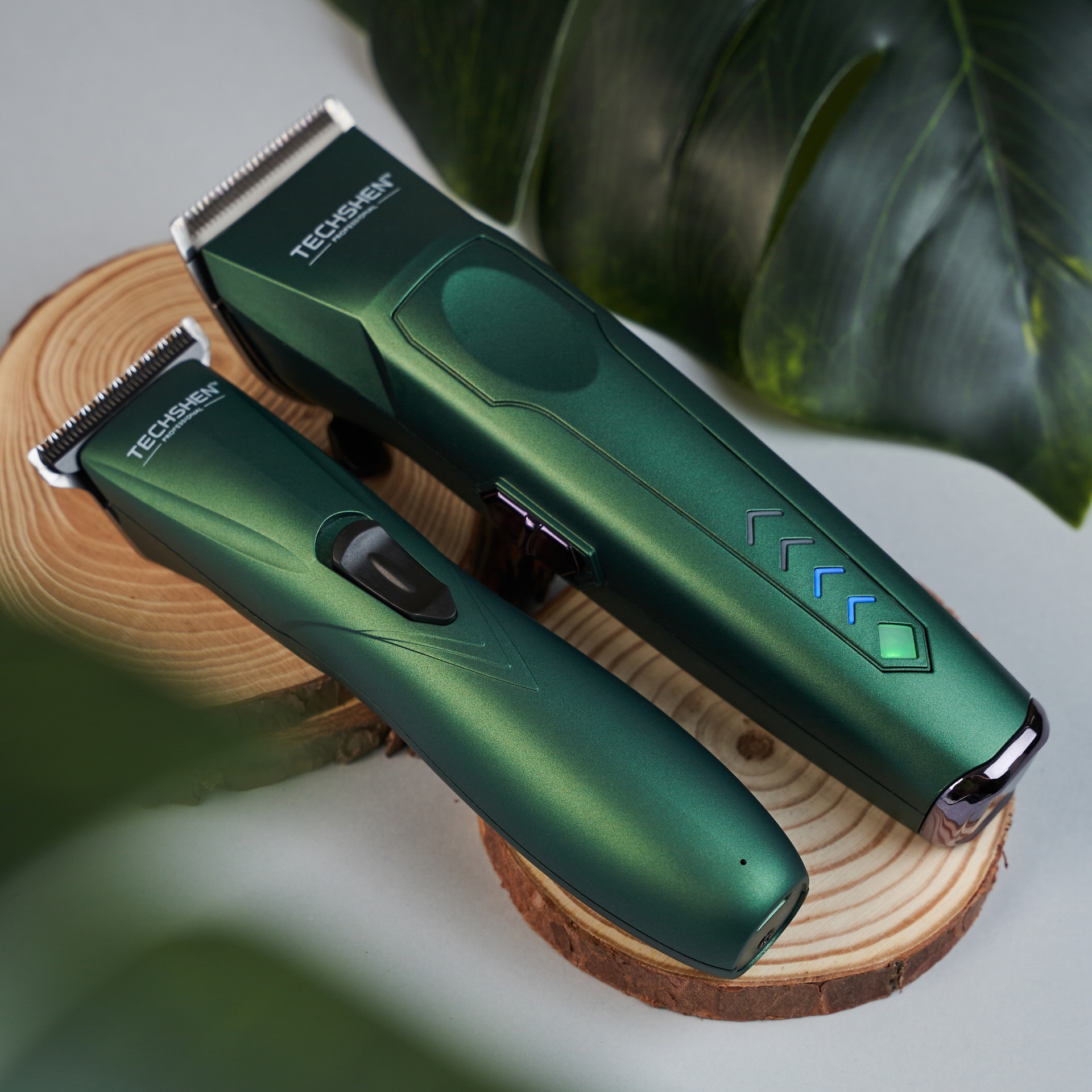 Aparelhos de barbear verdes TECHSHEN num pedestal de madeira com folhas verdes ao fundo