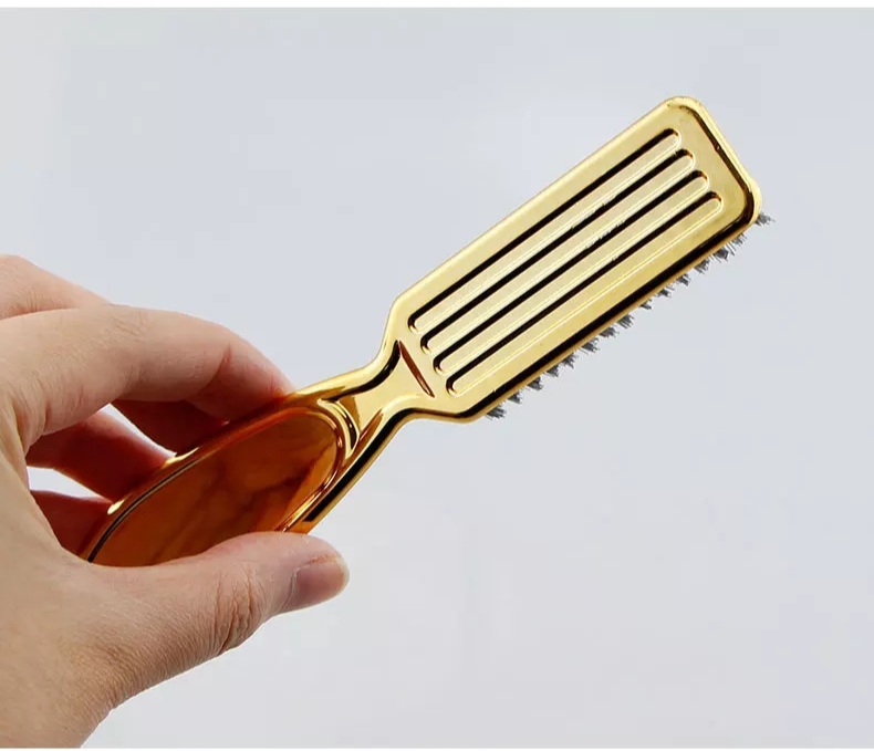 Escova de cabelo dourada com cerdas pretas.