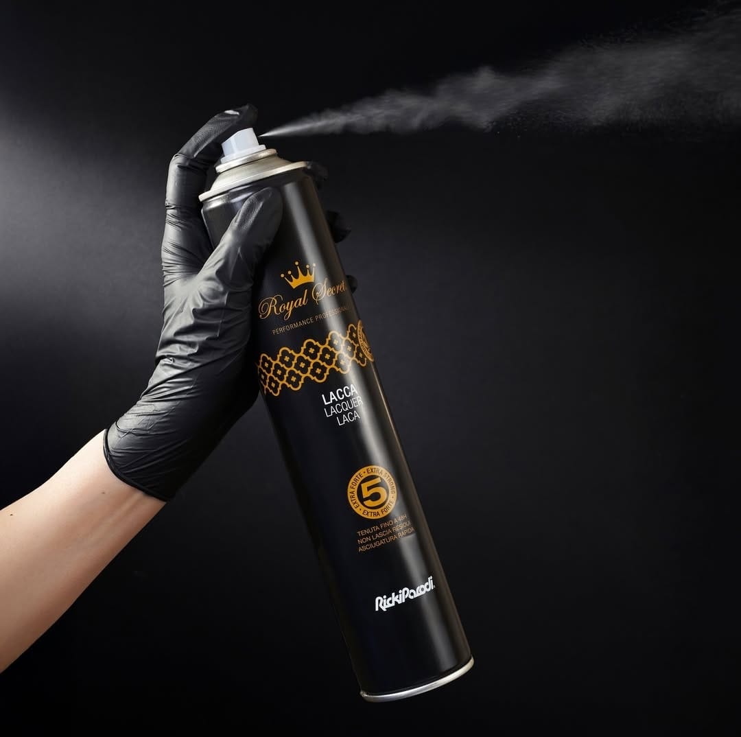 Mão com luva preta segurando spray preto de tinta da marca Royal a borrifar tinta