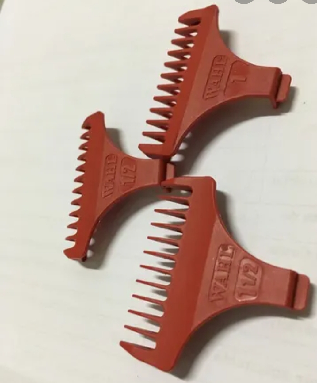 Três pentes de plástico cor de laranja com inscrições EMBOSSA WD e números 1/2 e 7.