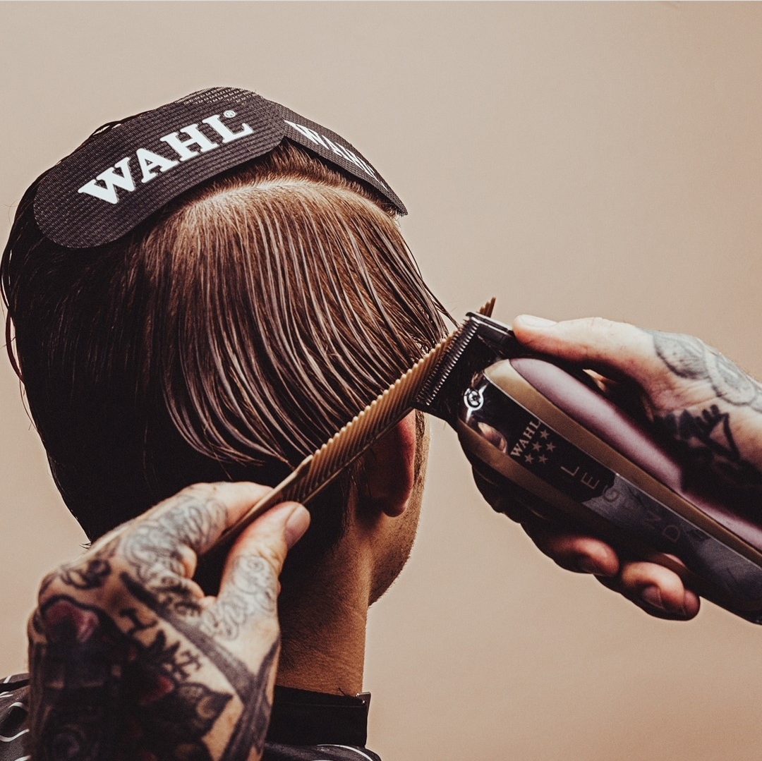 Aparelho de cortar cabelo WAHL aparando cabelo castanho com mãos tatuadas