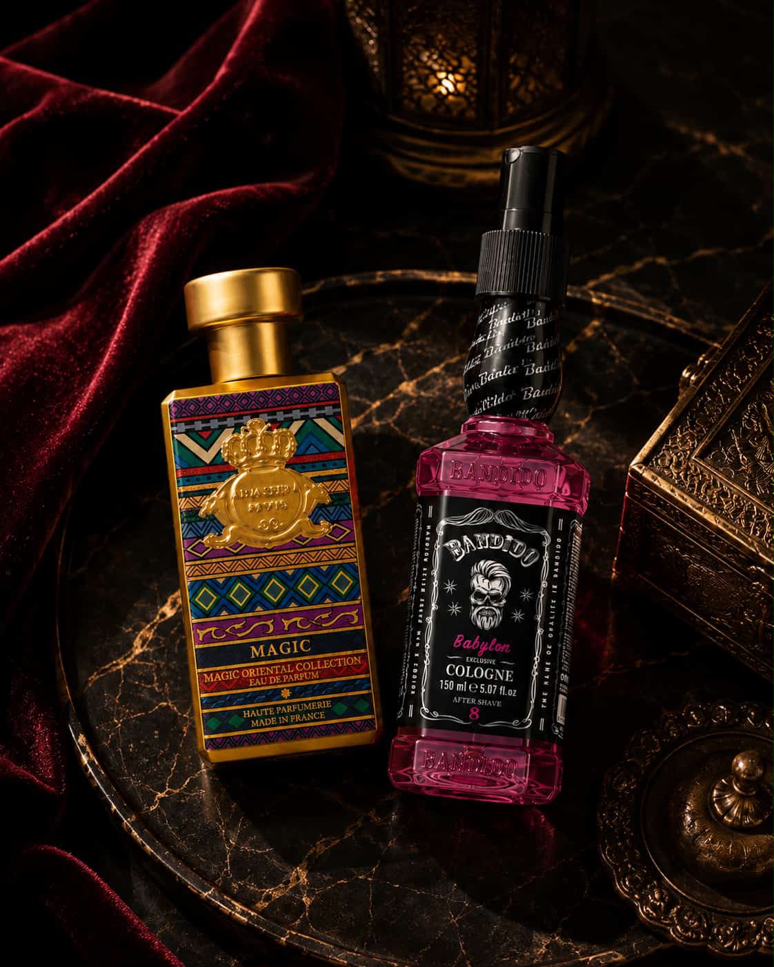 Duas garrafas de perfume coloridas numa bandeja de mármore com tecido vermelho e caixa dourada decorativa ao lado.