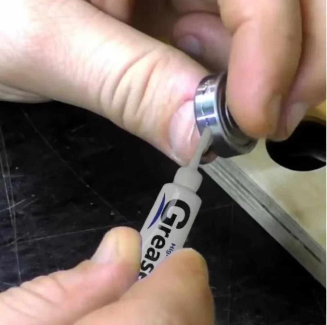 Mãos a aplicar óleo lubrificante numa peça metálica