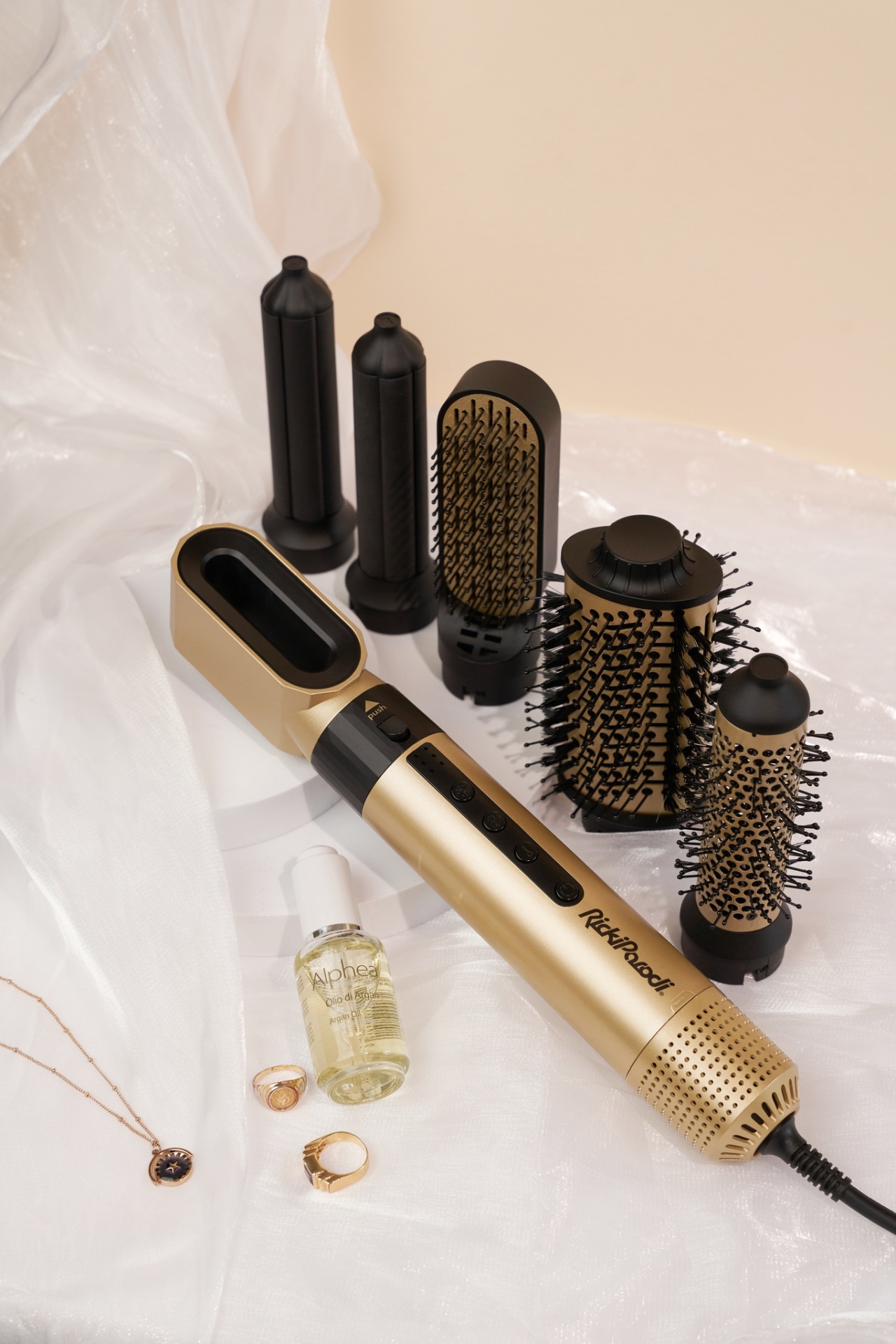 Modelador de cabelo dourado e preto com cinco acessórios e joalharia sobre tecido branco