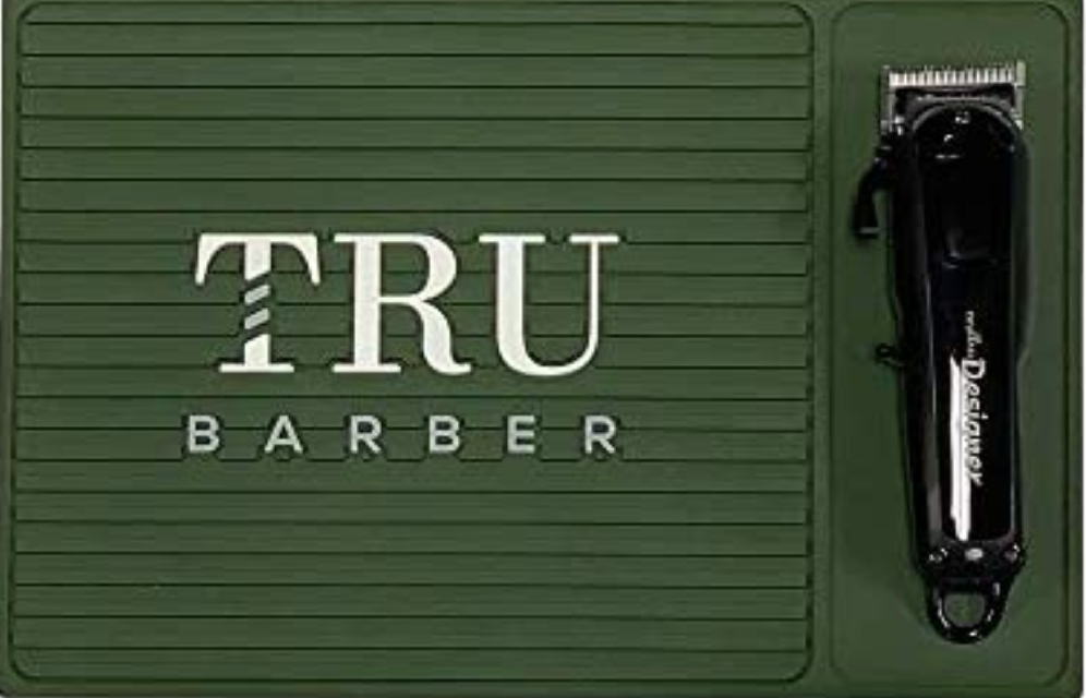 Aparador de cabelo elétrico preto numa base verde escura com o texto TRU BARBER