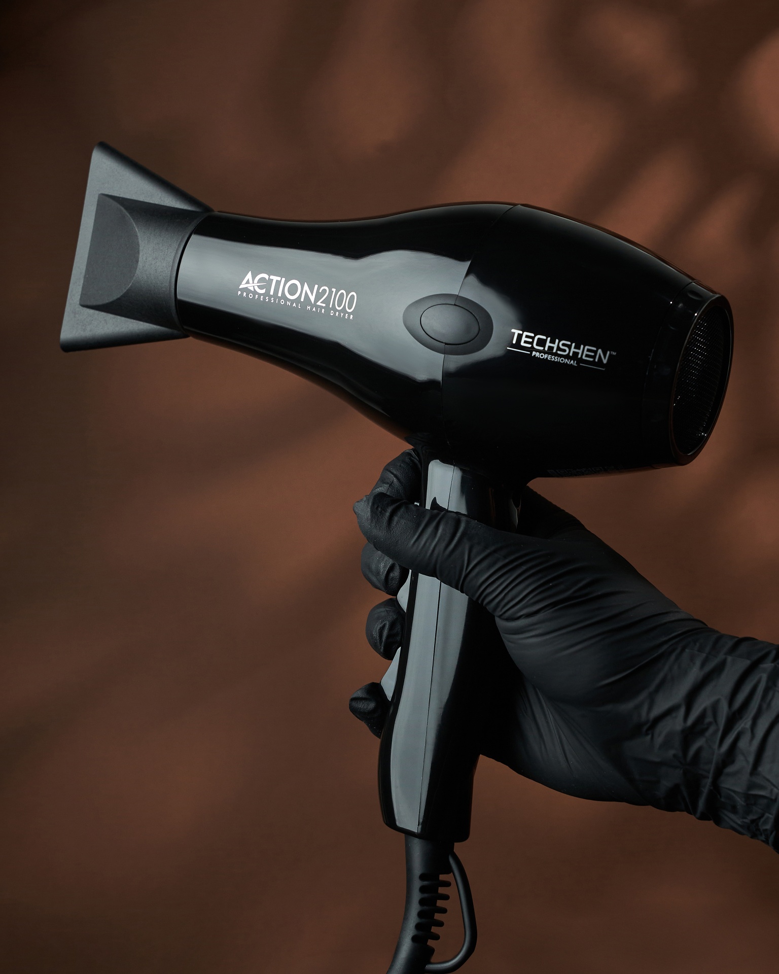 Secador de cabelo preto brilhante com texto branco segurado por mão com luva preta