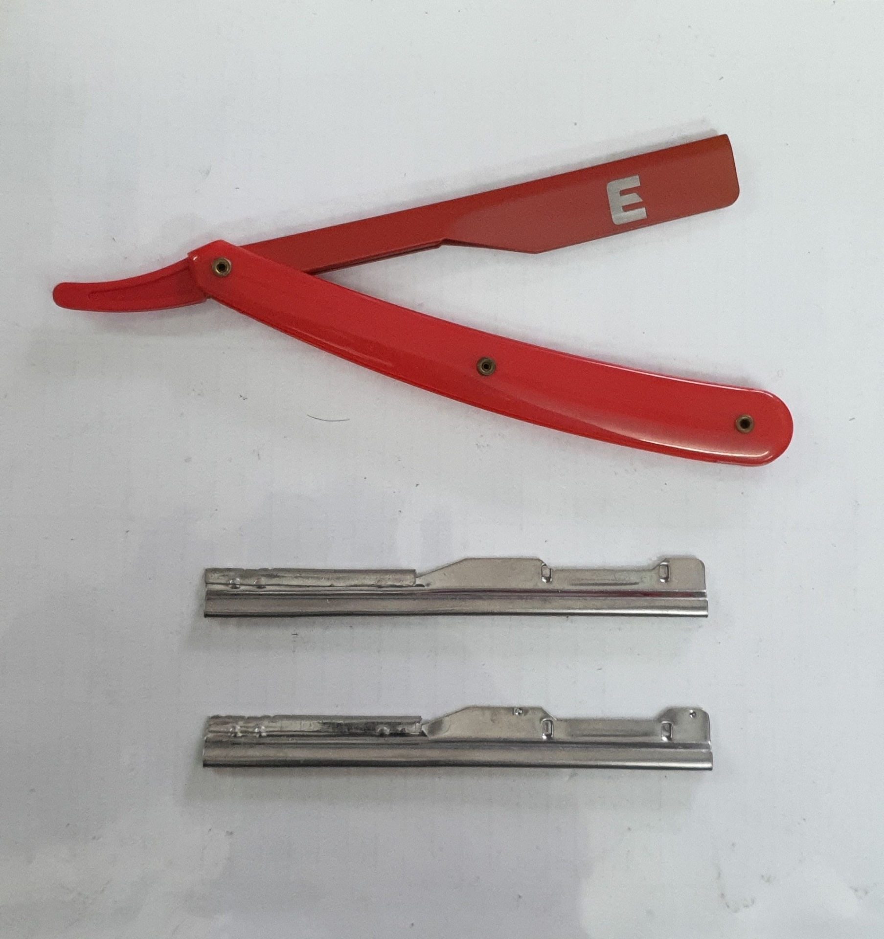 Navaja de barbear vermelha com lâminas metálicas sobre fundo branco