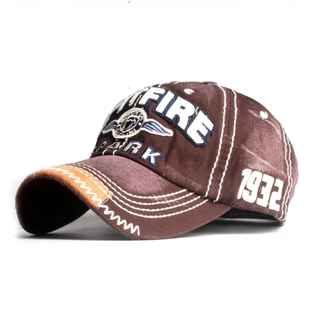 Boné de tecido marrom com bordados e costuras em branco e detalhes em laranja