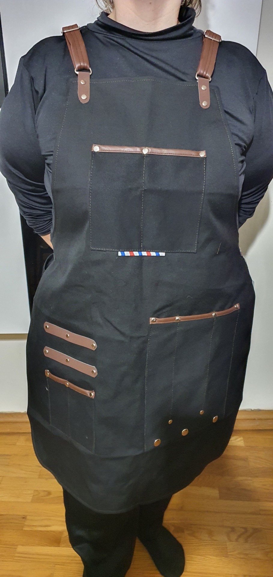 Avental preto com detalhes castanhos e bolsos múltiplos