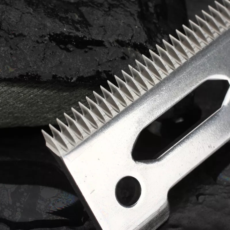 Lâmina metálica afiada de máquina de cortar cabelo sobre fundo preto molhado