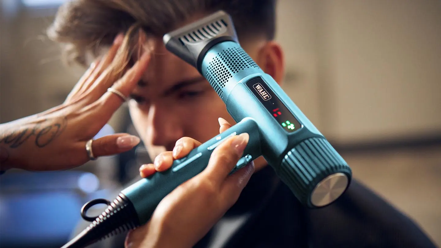 Máquina de cortar cabelo azul WAHL em uso numa barbearia