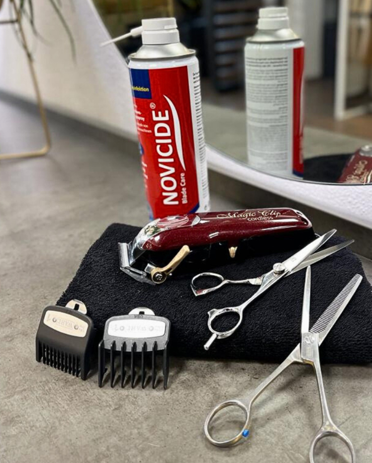 Kit de cabeleireiro com gel NOVICIDE, máquina, tesouras e pentes sobre toalha preta