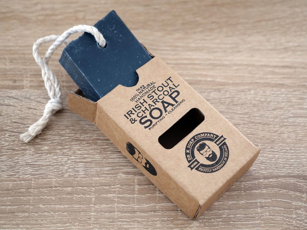 Sabonete preto em barra com cordão branco em embalagem de cartão castanho