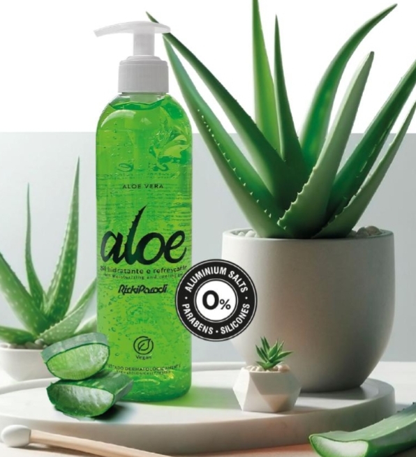 Frasco verde de gel hidratante de aloe vera com plantas de aloe vera em vasos brancos numa mesa branca