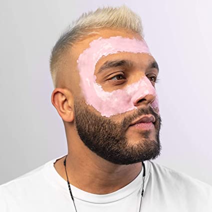 Homem com máscara facial cor-de-rosa em formato circular no rosto, cabelo loiro e barba escura