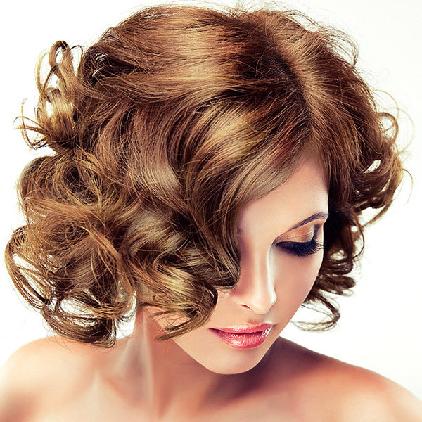 Mulher com cabelo castanho ondulado e maquilhagem suave