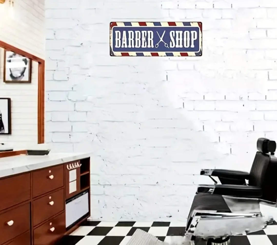 Cadeira de barbeiro preta e móveis de madeira junto a parede branca com placa 'BARBER SHOP'