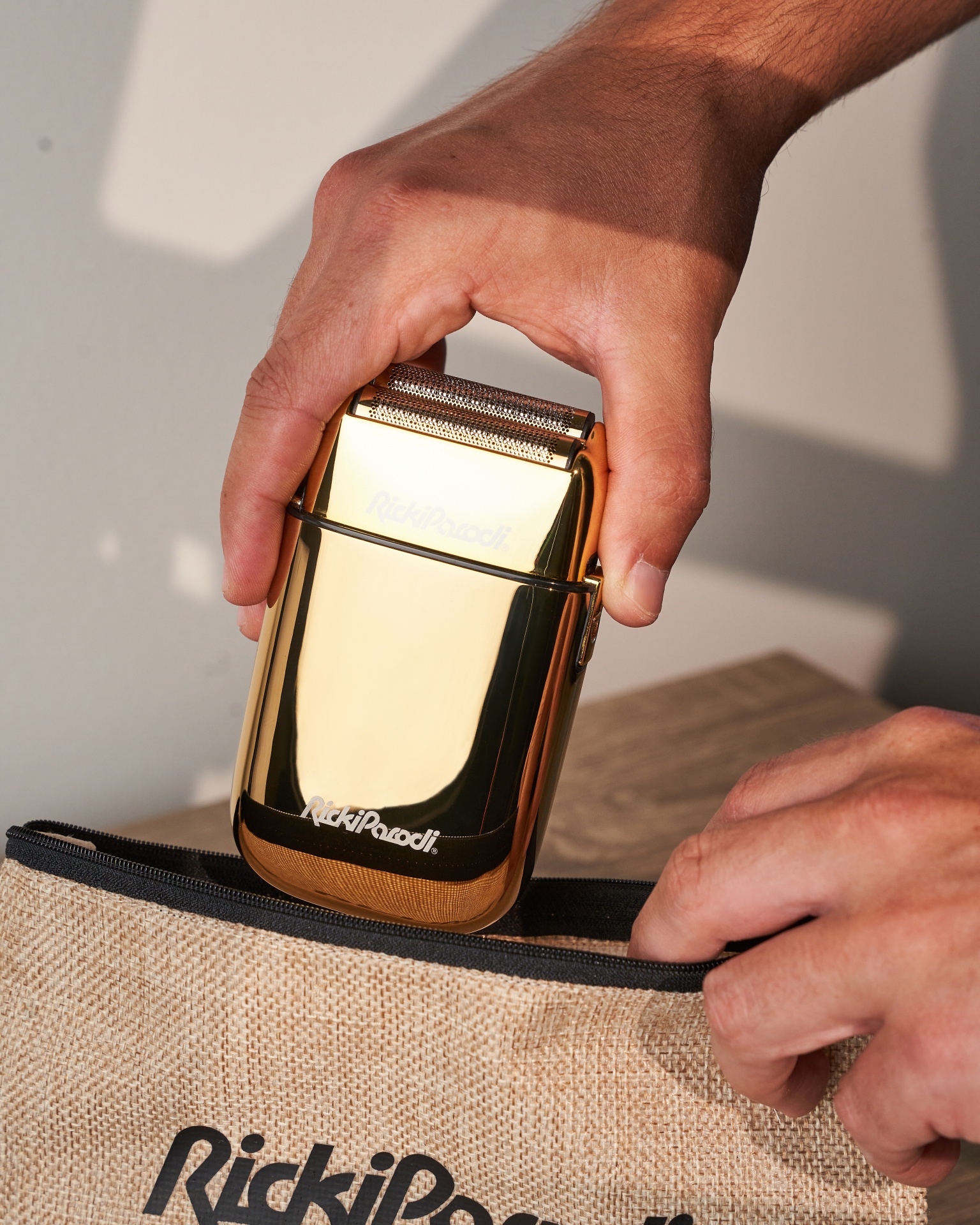 Aparelho de barbear dourado sendo retirado de bolsa de tecido