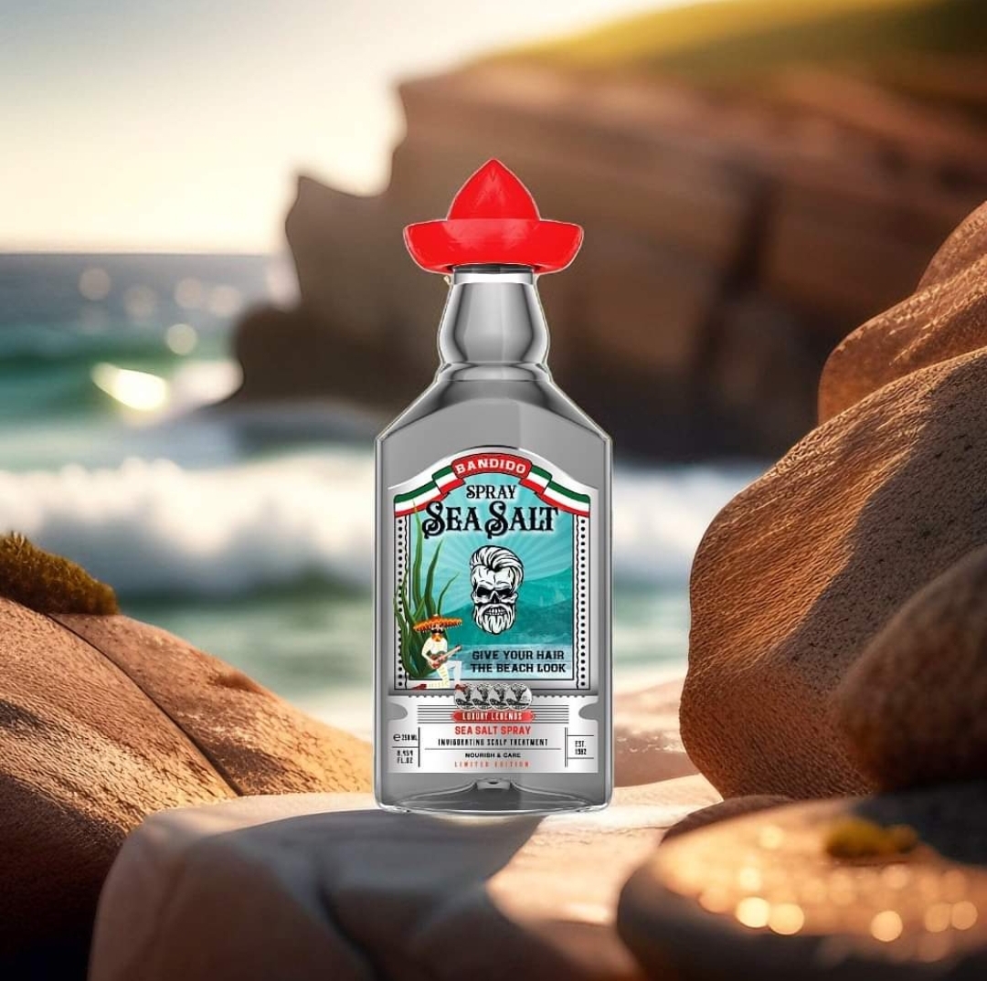 Garrafa de spray de sal marinho Bandidos com tampo vermelho e rótulo azul sobre pedras perto do mar