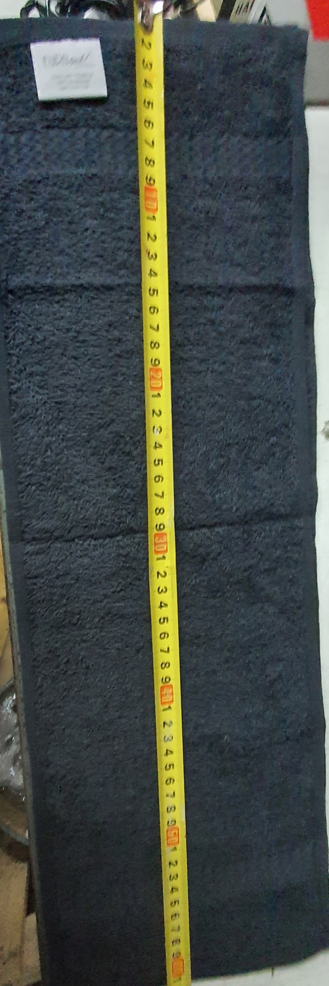 Toalha preta quadrada com fita métrica amarela medindo cerca de 90 cm