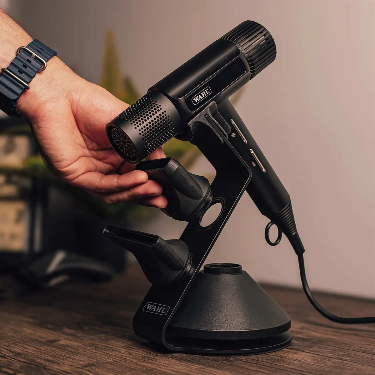 Secador de cabelo preto da marca WAHL com suporte e acessórios sobre superfície de madeira.