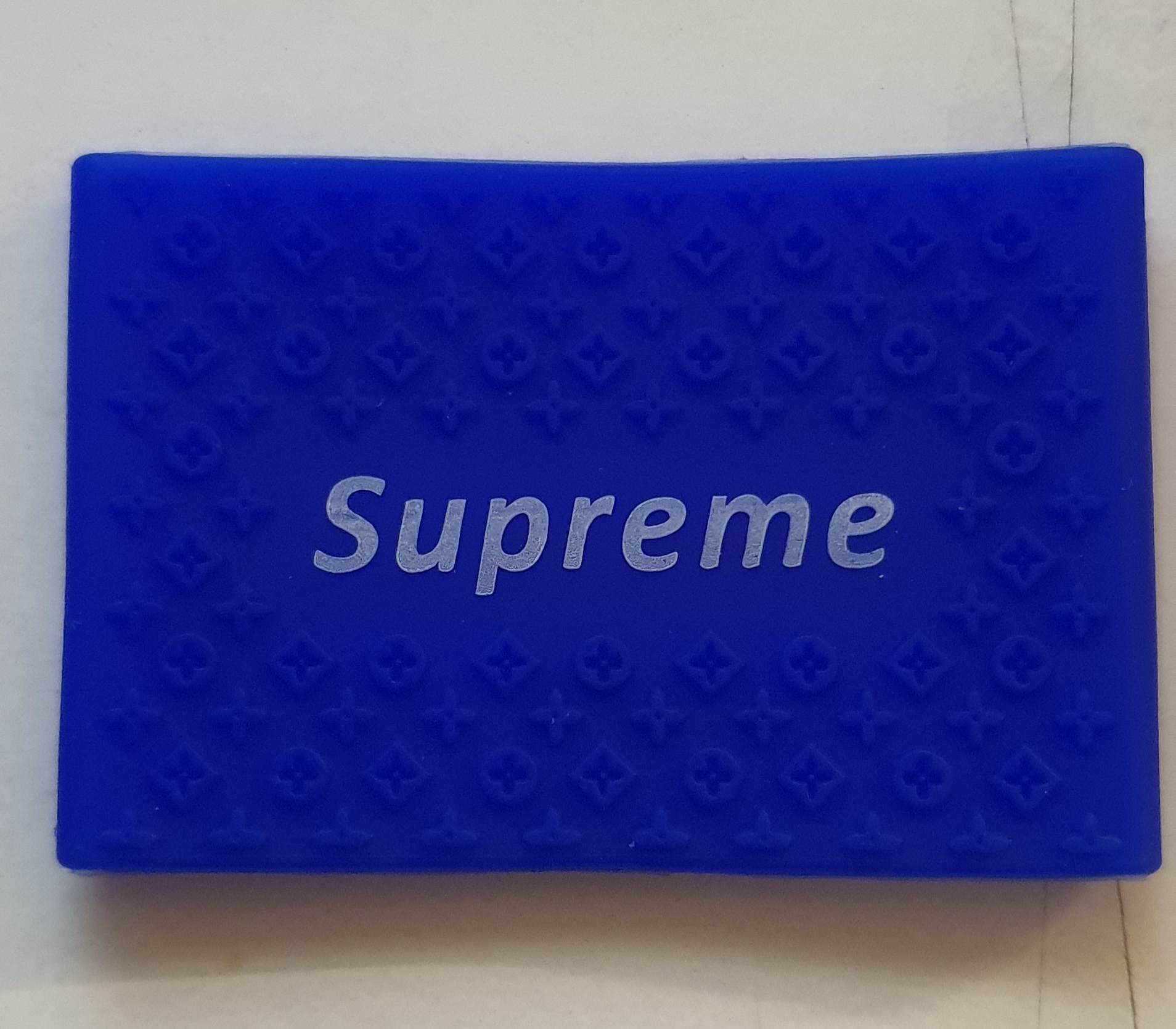 Cartão azul com a palavra Supreme e padrão em relevo