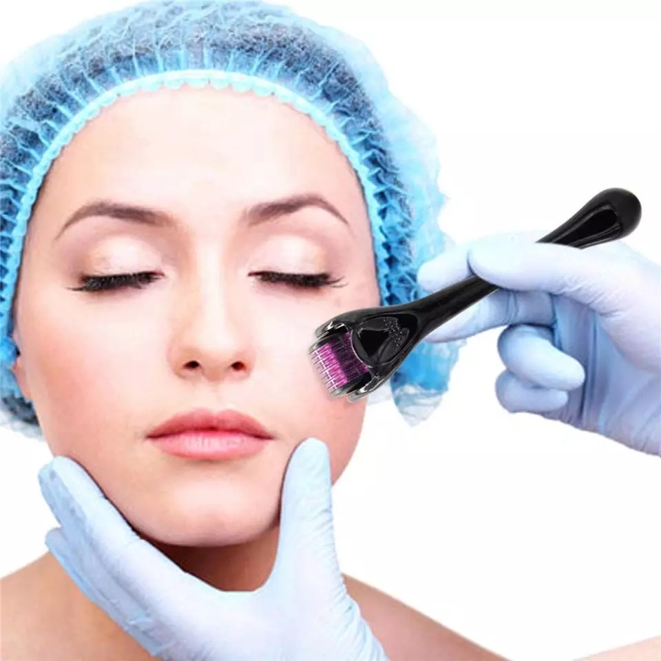 Mulher com touca azul recebendo tratamento facial com dispositivo preto com agulhas.