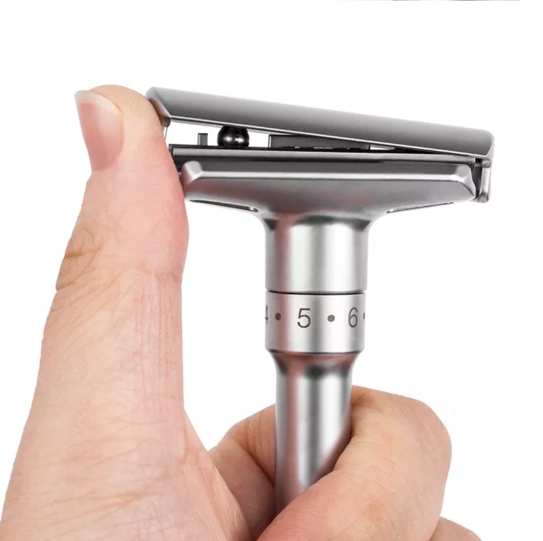 Máquina de barbear metálica prateada com ajustes numerados em fundo branco