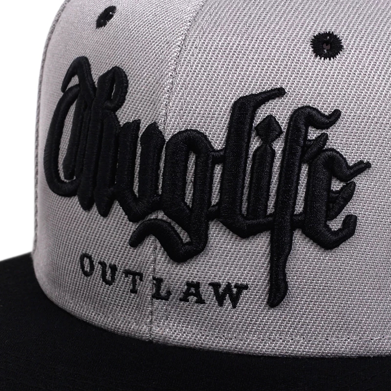 Boné cinza com aba preta e bordado preto com os textos thuglife e OUTLAW