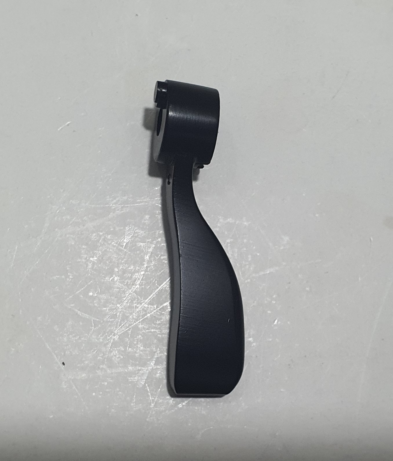 Peça de plástico preto curvo sobre superfície branca riscada