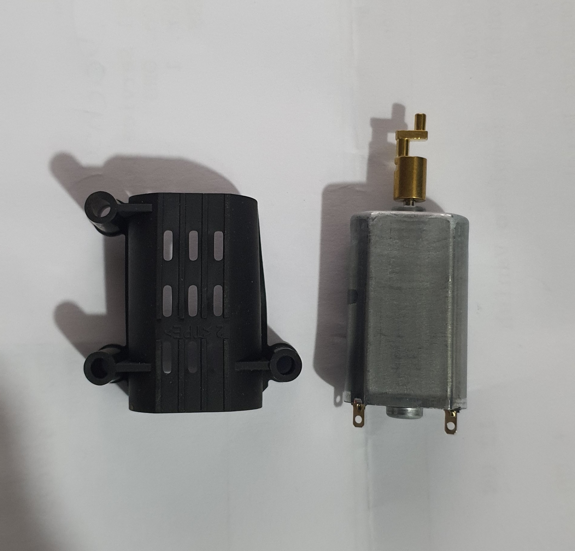 Motor elétrico cinza com capa plástica preta ao lado