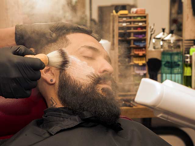 Homem com barba a receber tratamento facial numa barbearia