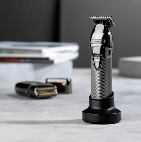 Aparelho de barbear elétrico preto e cinza com base preta numa superfície cinzenta