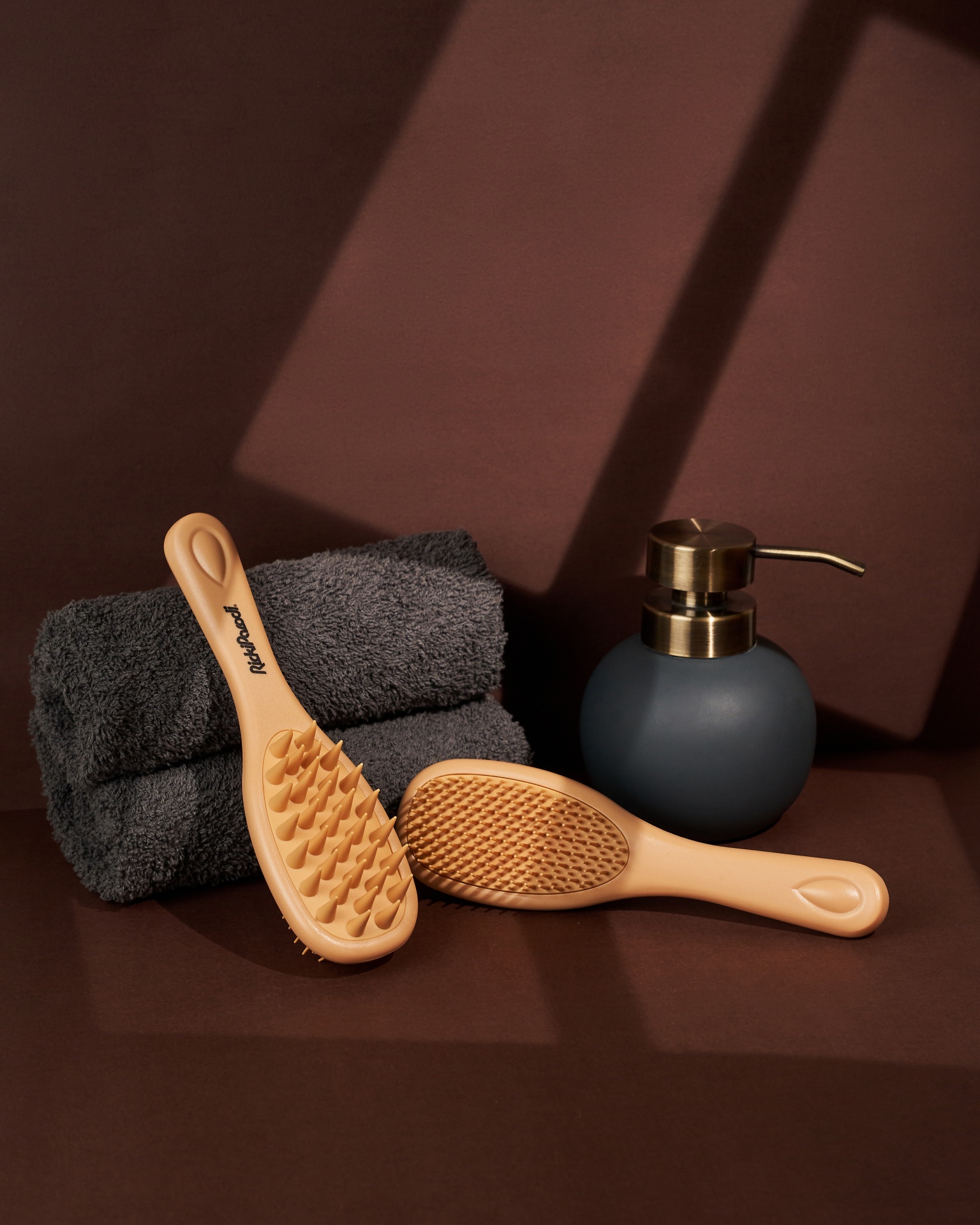 Massageadores de mão silicone areia ao lado de toalhas cinza e dispenser azul