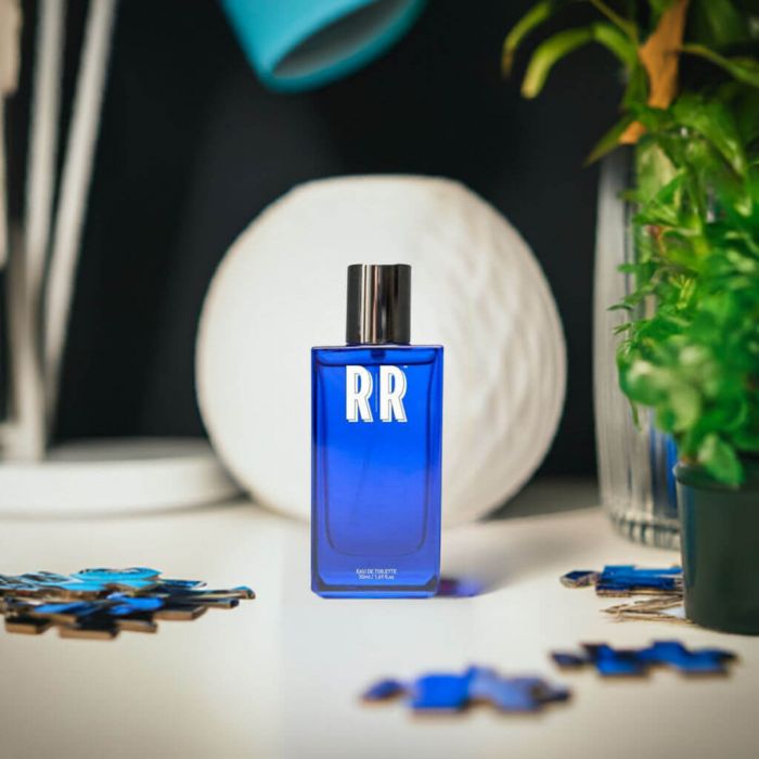 Frasco azul de vidro para eau de toilette com tampa prateada e texto RR