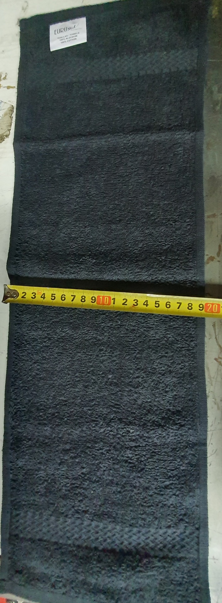 Toalha de banho preta com etiqueta e fita métrica amarela