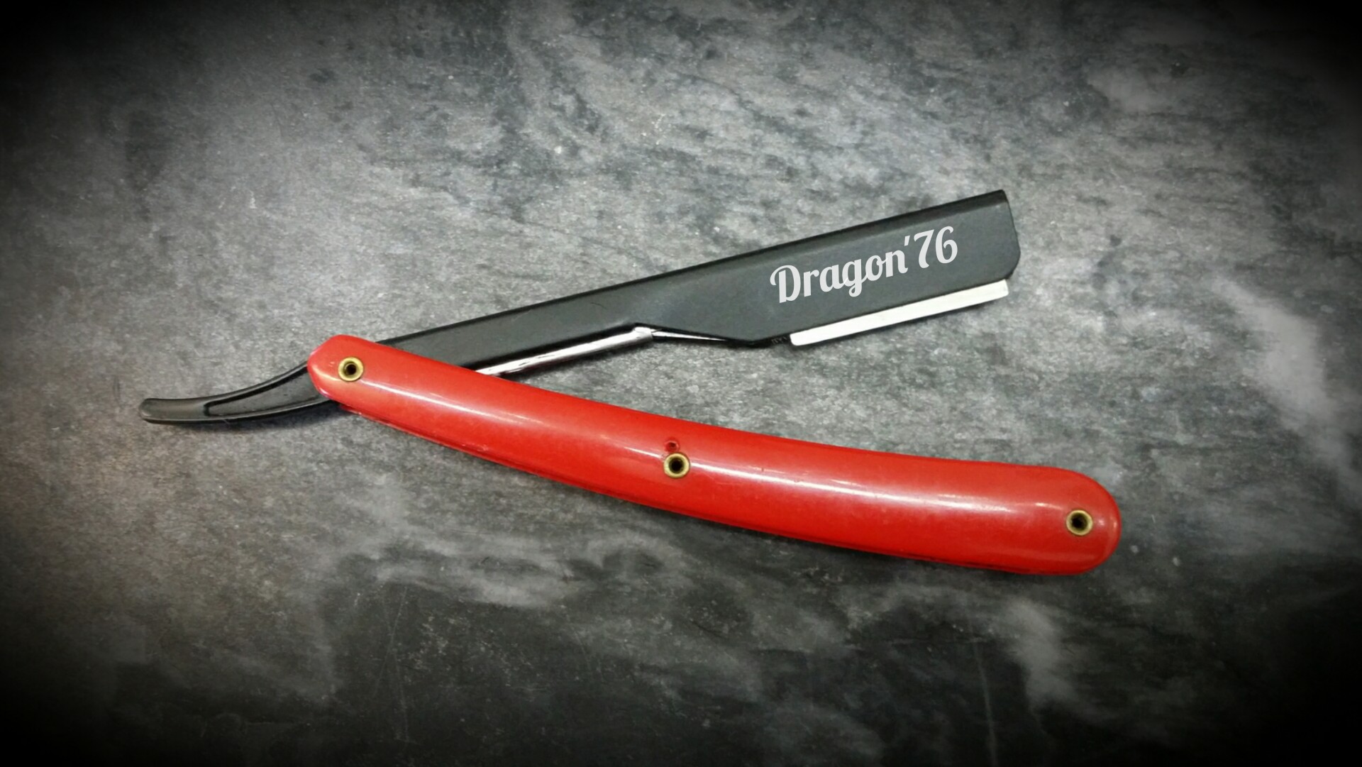 Navalha de barbear com cabo vermelho e lâmina preta com texto 'Dragon 76'