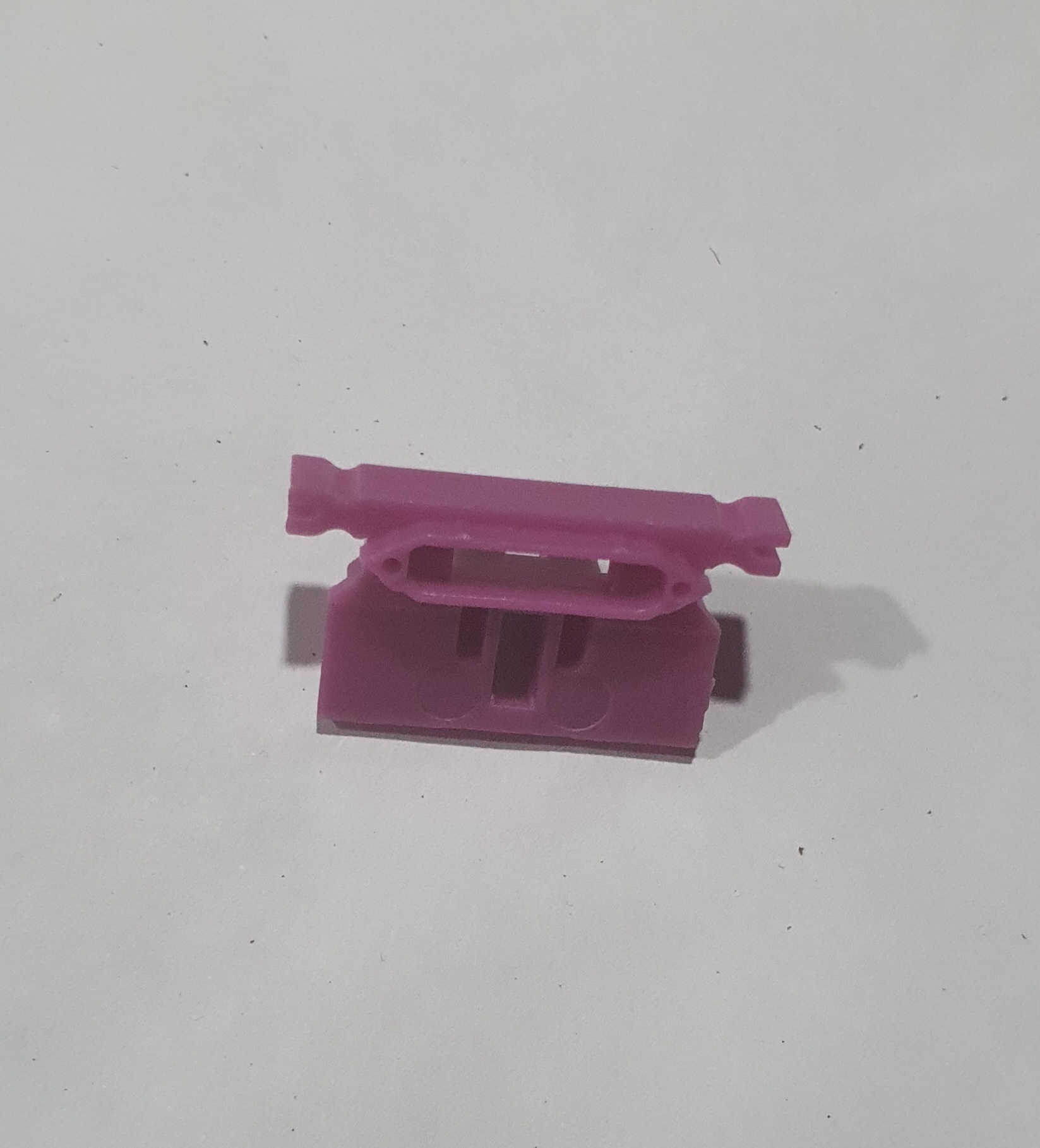 Peça plástica roxa sobre fundo branco